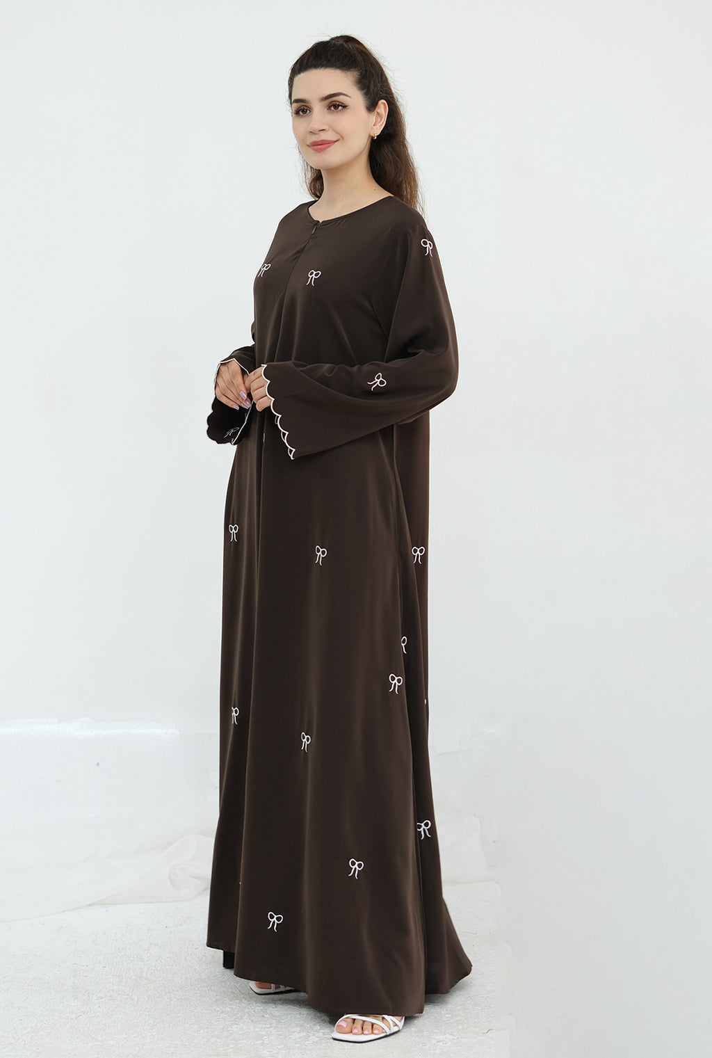 Woman wearing a brown dress with white patterns on a white background
