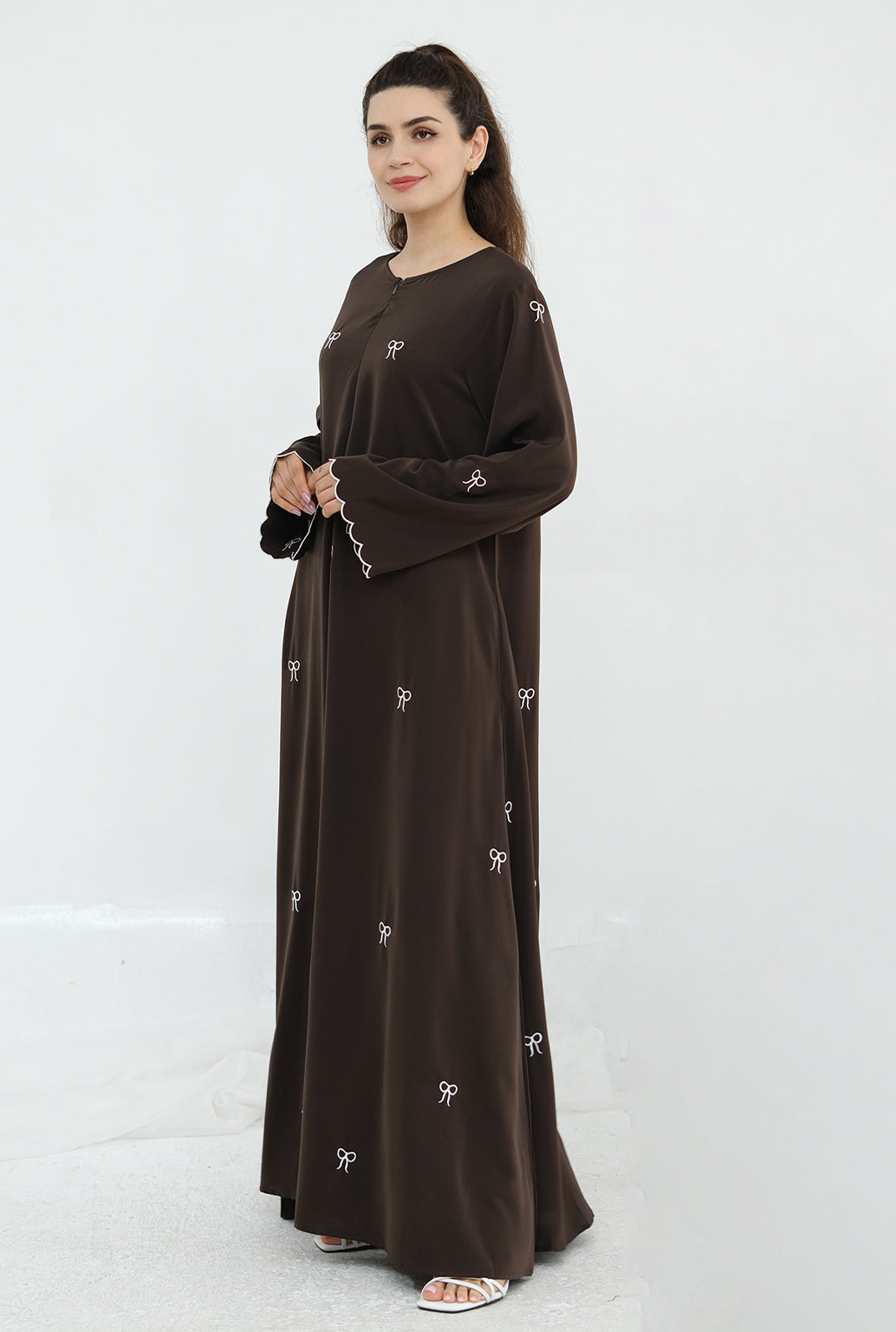 Woman wearing a brown dress with white patterns on a white background