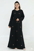 Woman wearing a black dress with pink embroidery on a white background