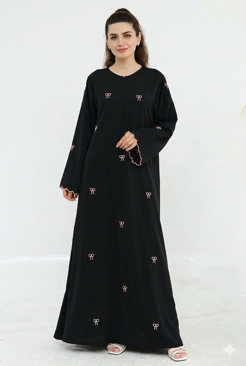 Woman wearing a black dress with pink embroidery on a white background