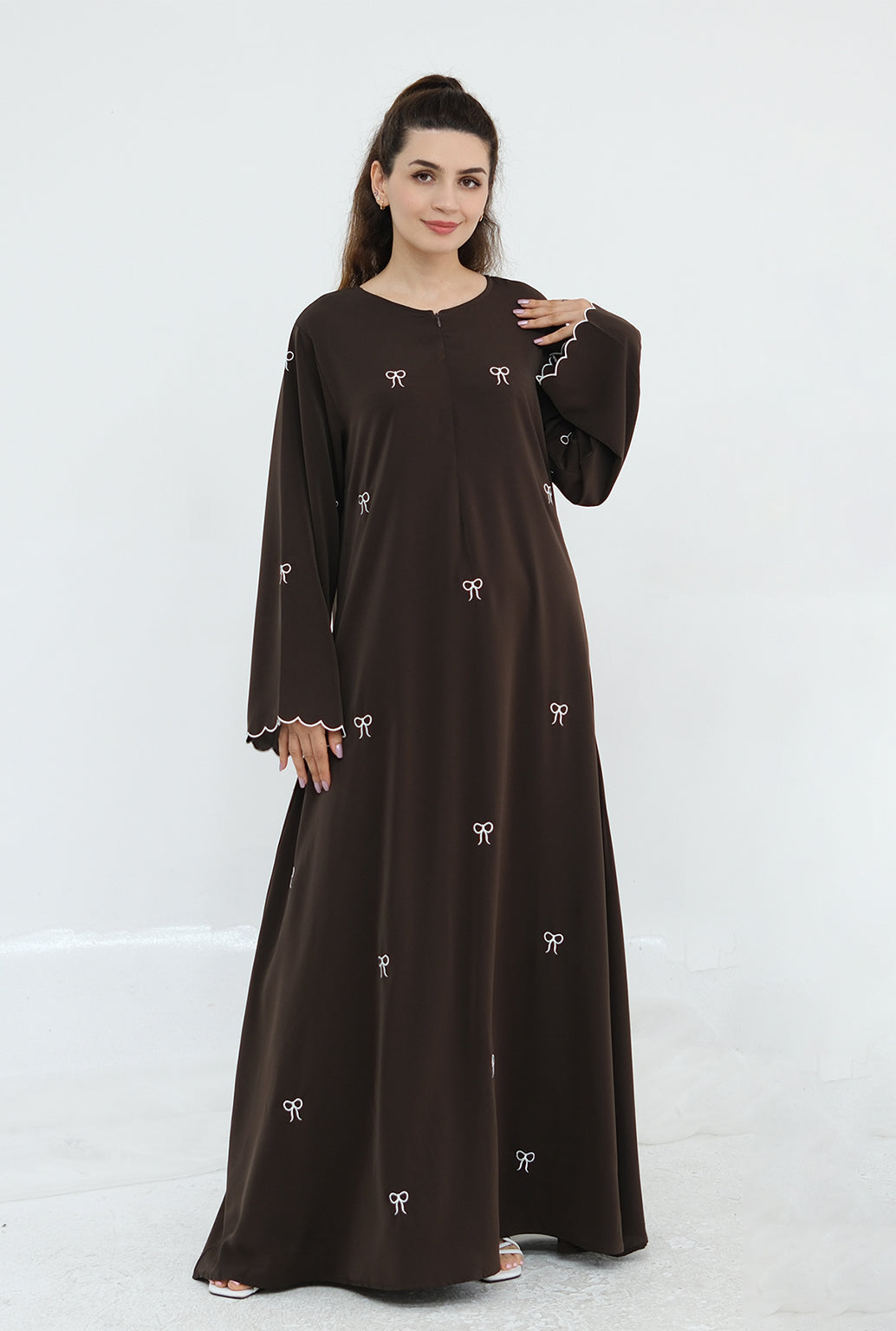 Woman wearing a brown dress with white patterns on a white background