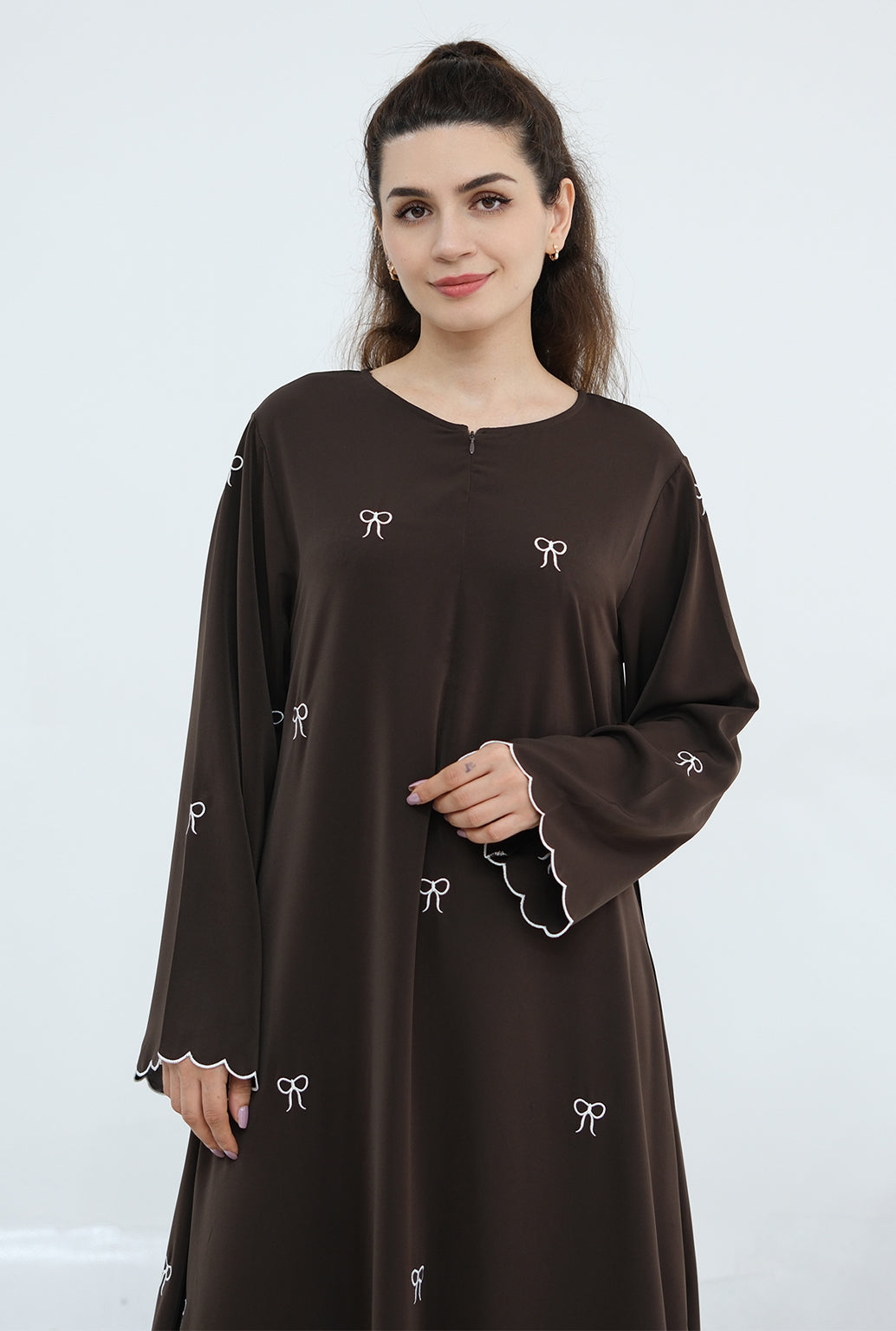 Woman wearing a brown dress with white embroidery on a white background