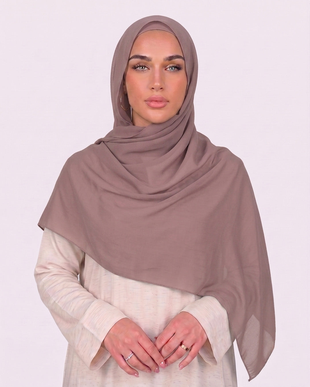 Model wearing a lightweight, nude muave chiffon hijab wrapped elegantly over a beige long-sleeved dress.