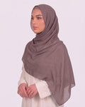 Model wearing a lightweight, nude muave chiffon hijab wrapped elegantly over a beige long-sleeved dress.