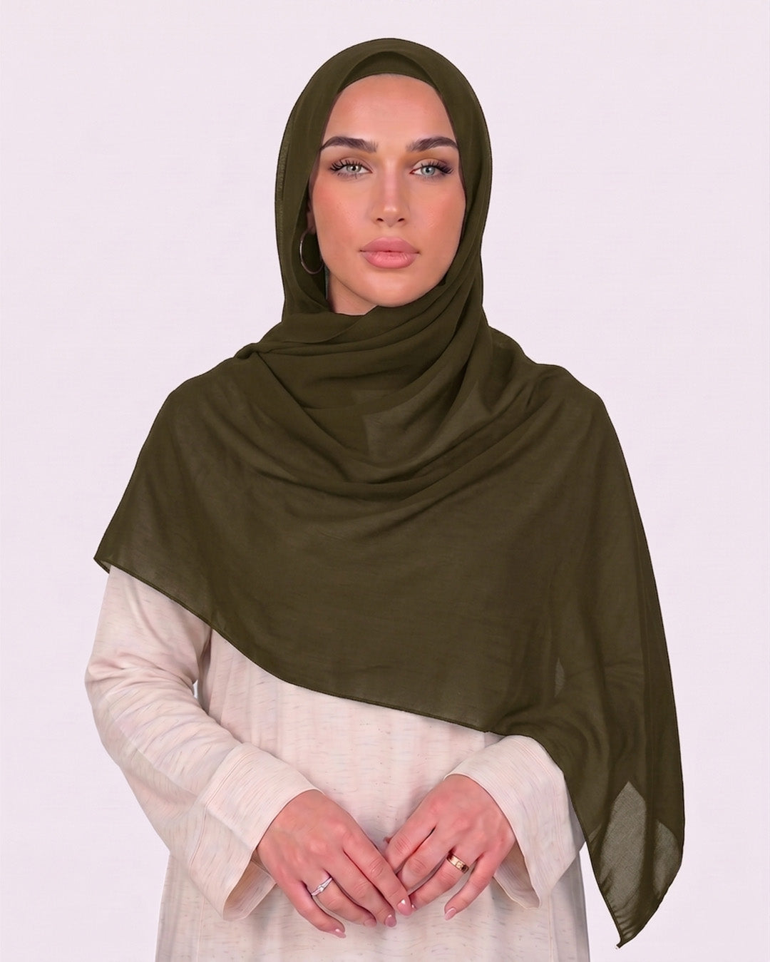 Model wearing a lightweight, olive chiffon hijab wrapped elegantly over a beige long-sleeved dress.