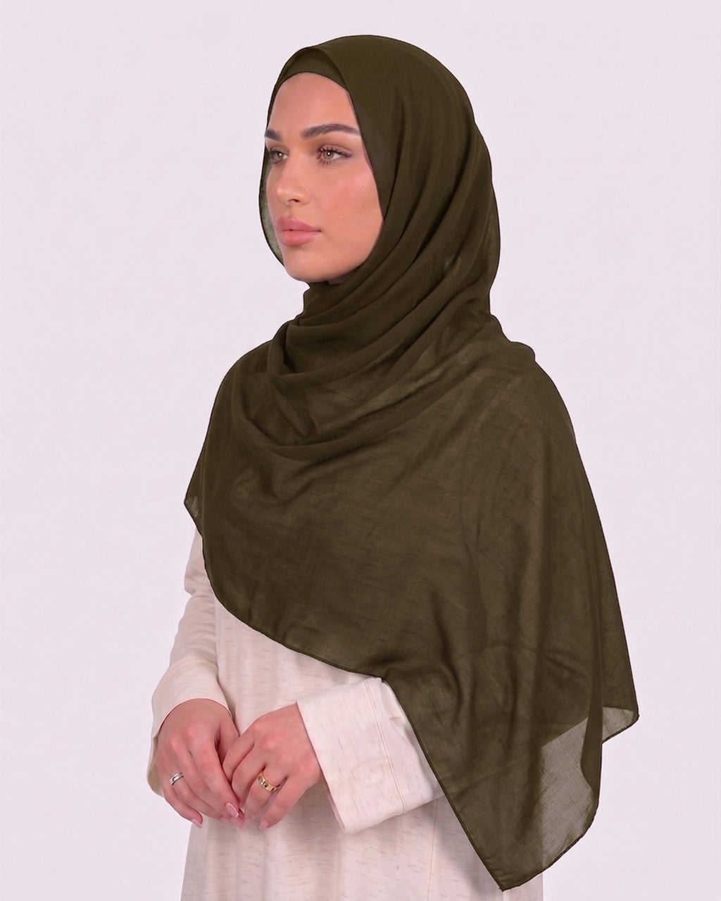 Model wearing a lightweight, olive chiffon hijab wrapped elegantly over a beige long-sleeved dress.