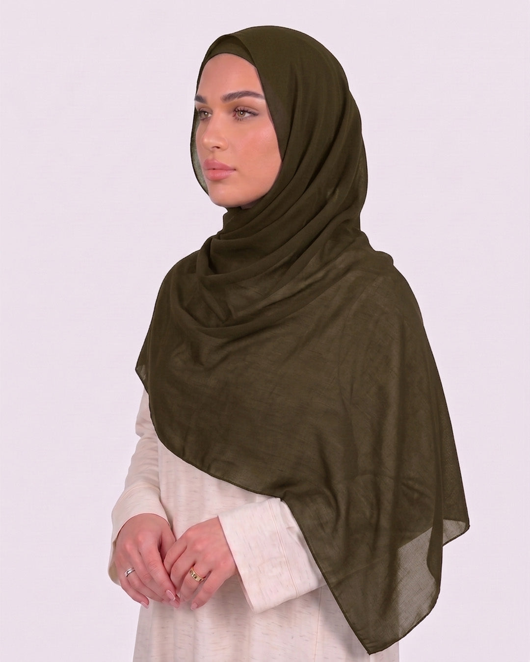 Model wearing a lightweight, olive chiffon hijab wrapped elegantly over a beige long-sleeved dress.