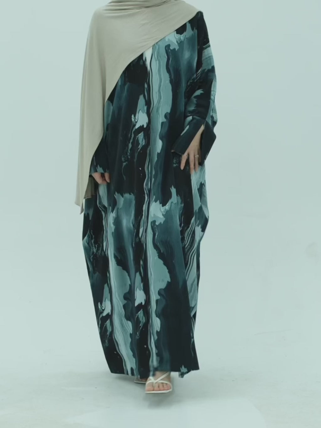 Marbled patterned dresses on a gold clothing rack against a white background