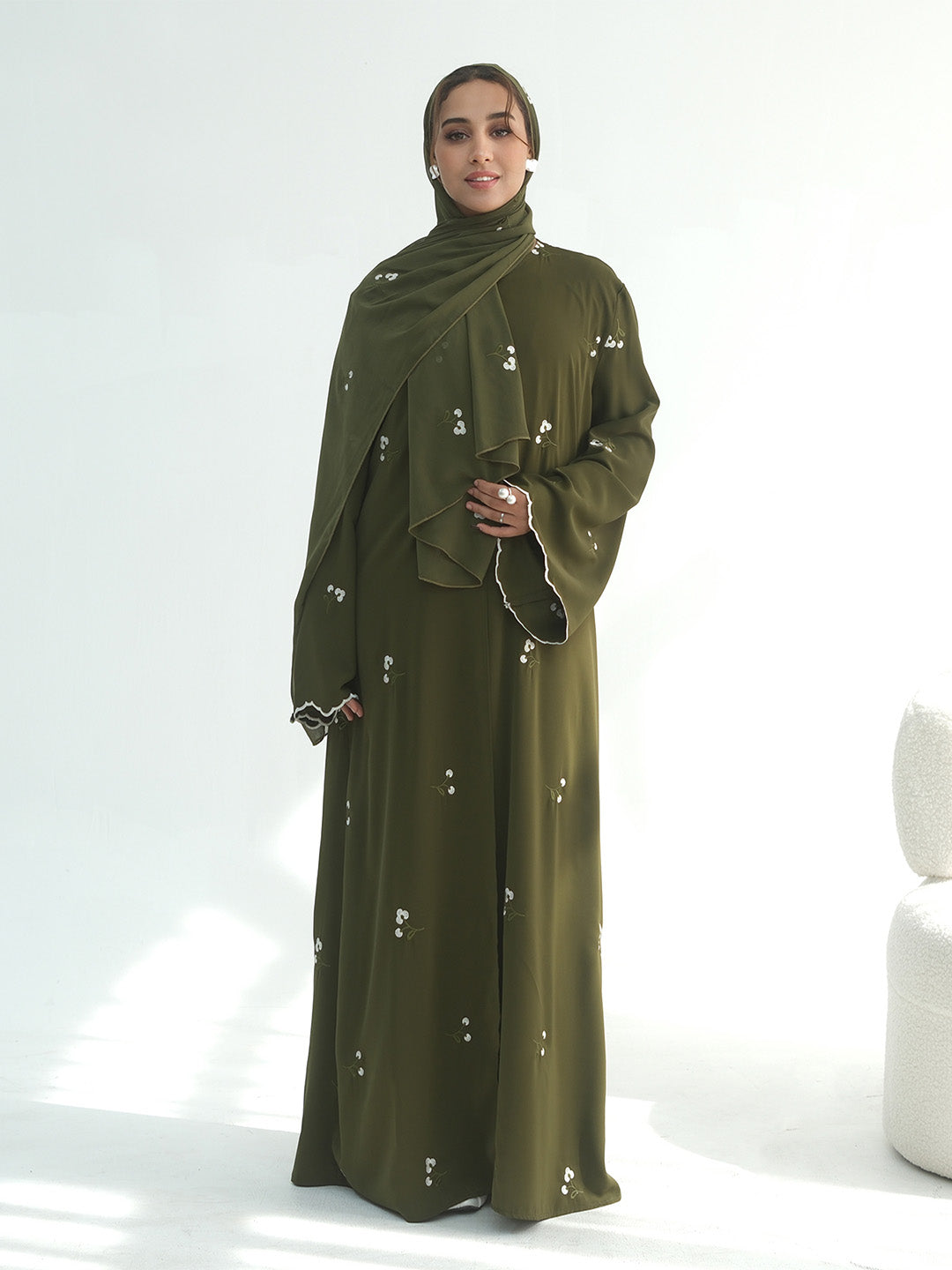 A mannequin wearing a dusty rose , army green and coffee abaya and matching hijab, shown from the back. The abaya features small white embroidered details scattered across the fabric.