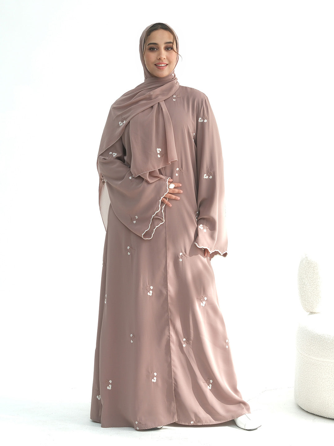A mannequin wearing a dusty rose , army green and coffee abaya and matching hijab, shown from the back. The abaya features small white embroidered details scattered across the fabric.