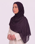 Model wearing a lightweight, purple chiffon hijab wrapped elegantly over a beige long-sleeved dress.