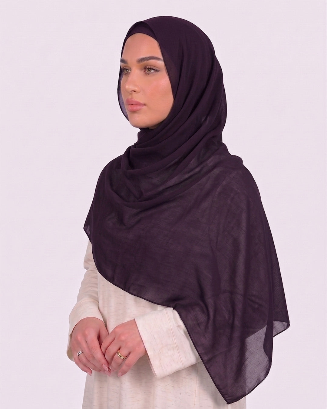 Model wearing a lightweight, purple chiffon hijab wrapped elegantly over a beige long-sleeved dress.