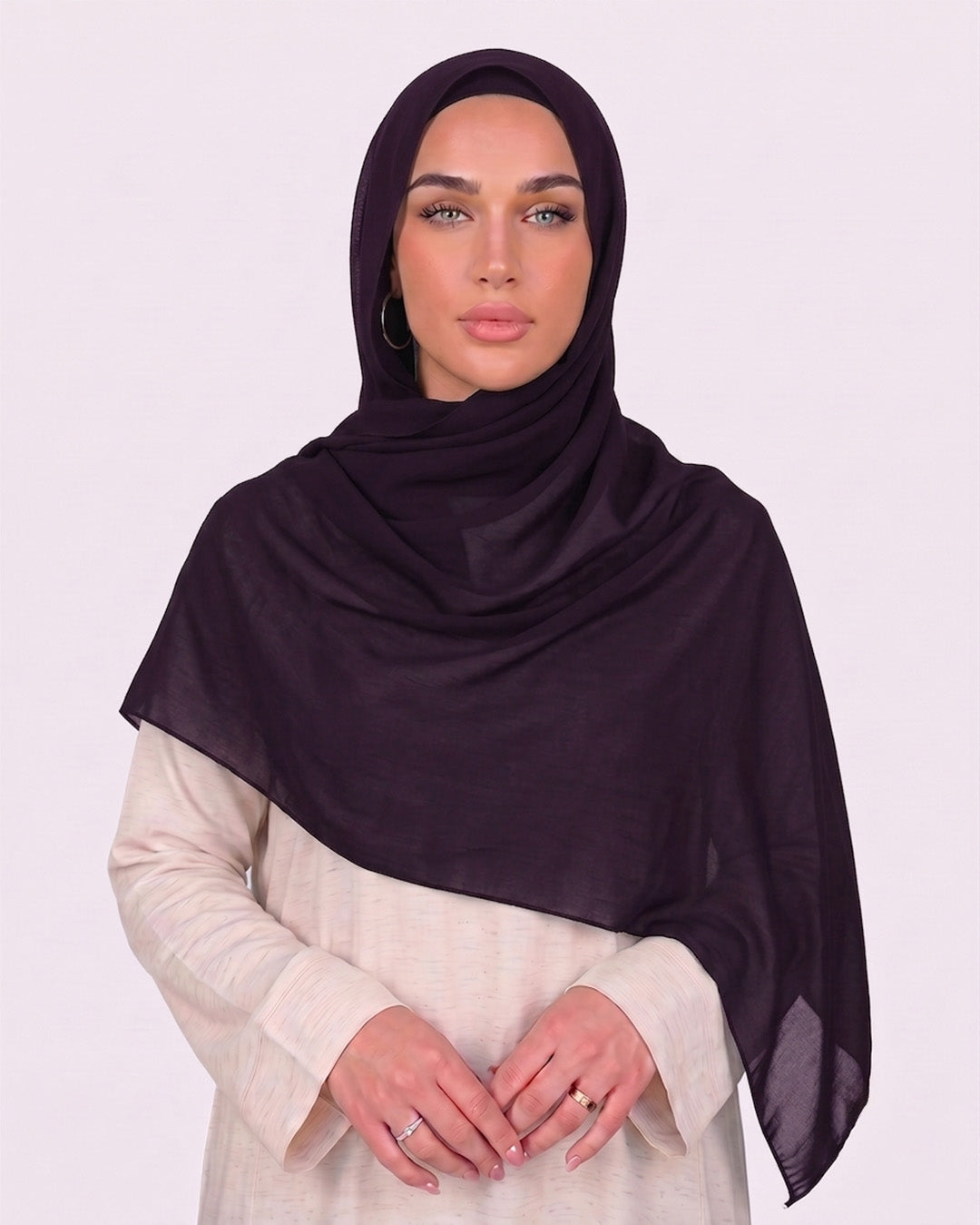 Model wearing a lightweight, purple chiffon hijab wrapped elegantly over a beige long-sleeved dress.