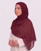 Model wearing a lightweight, rose red chiffon hijab wrapped elegantly over a beige long-sleeved dress.