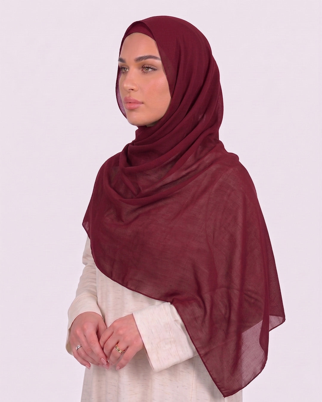 Model wearing a lightweight, rose red chiffon hijab wrapped elegantly over a beige long-sleeved dress.