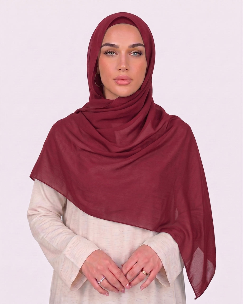 Model wearing a lightweight, rose red chiffon hijab wrapped elegantly over a beige long-sleeved dress.