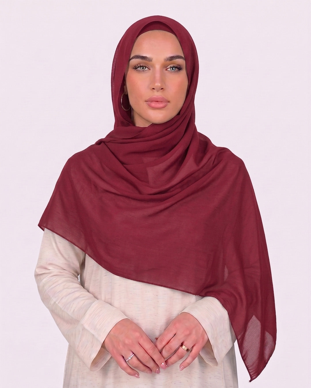 Model wearing a lightweight, rose red chiffon hijab wrapped elegantly over a beige long-sleeved dress.