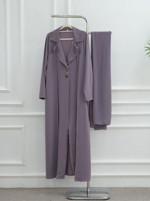 A two-piece women's outfit in a dusty lavender-purple color, consisting of a long-sleeve button-front coat with a collar and matching wide-leg trousers, displayed on a metal clothing rack against a white paneled wall.