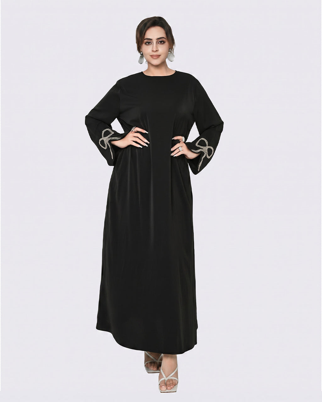 Woman wearing a black dress with decorative cuffs on a white background
