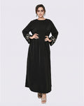 Woman wearing a black dress with decorative cuffs on a white background