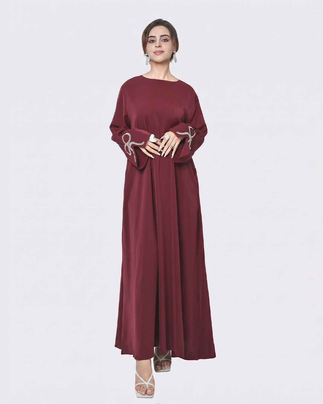 Woman wearing a burgundy dress with silver embroidery on a white background