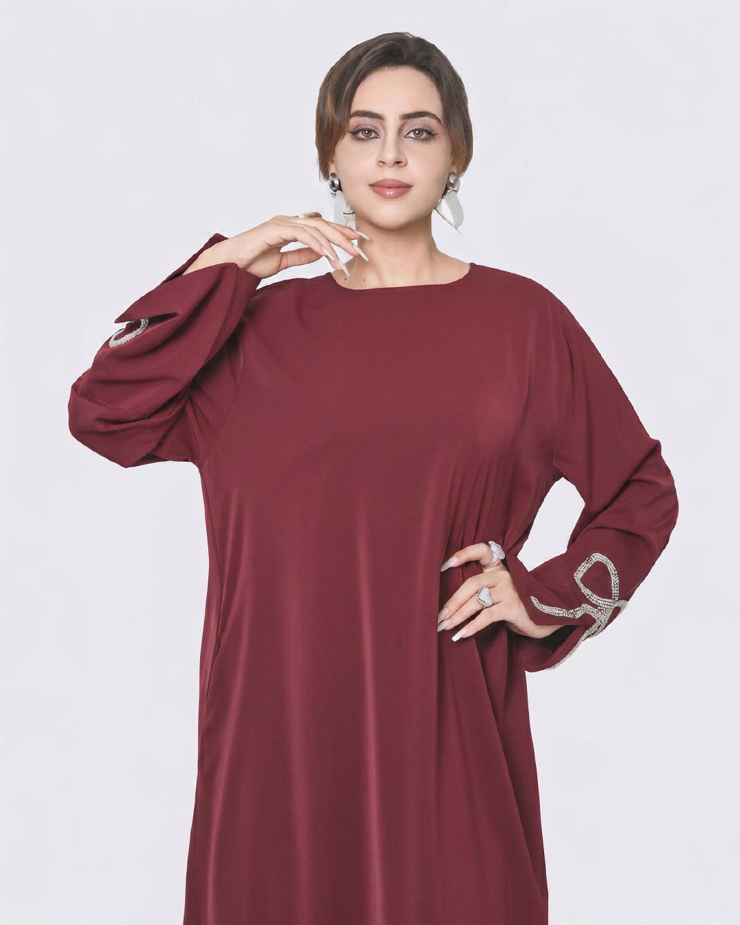 Woman wearing a burgundy dress with silver cuffs on a white background