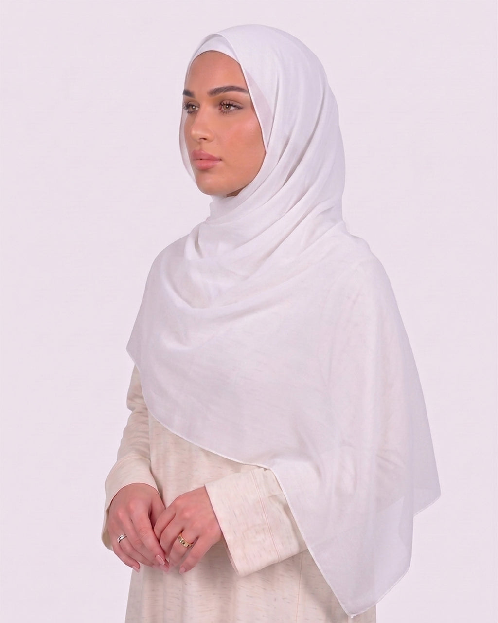 Model wearing a lightweight, white chiffon hijab wrapped elegantly over a beige long-sleeved dress.