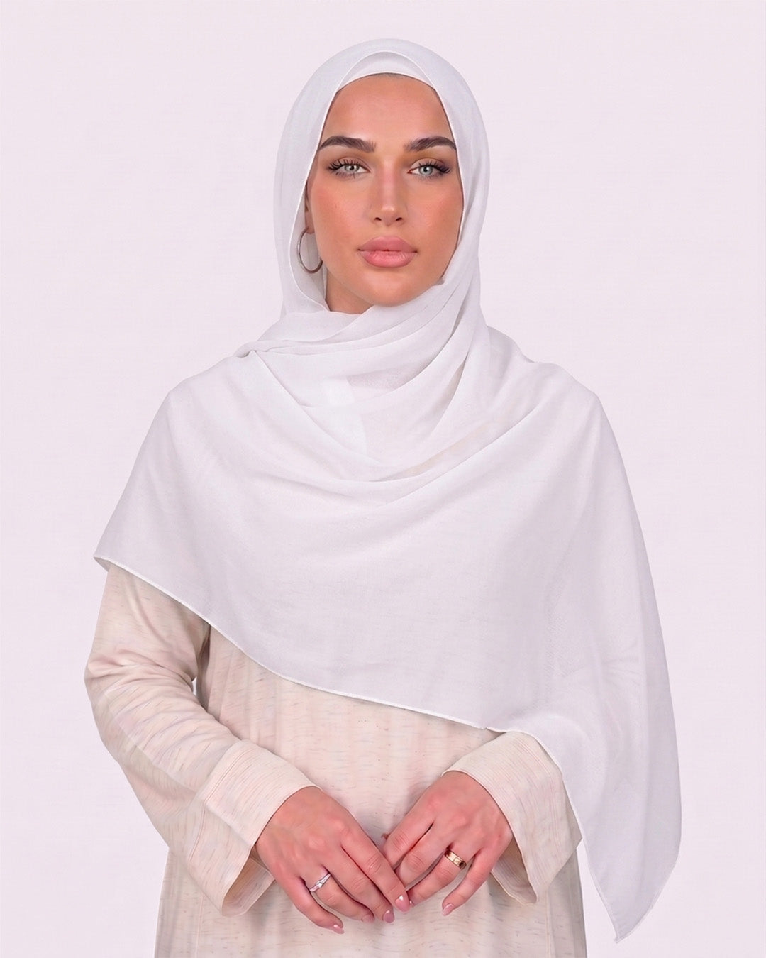 Model wearing a lightweight, white chiffon hijab wrapped elegantly over a beige long-sleeved dress.