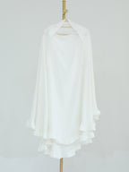 A white long-sleeve blouse with a high-low ruffled hem, displayed on a hanger against a light gray background.