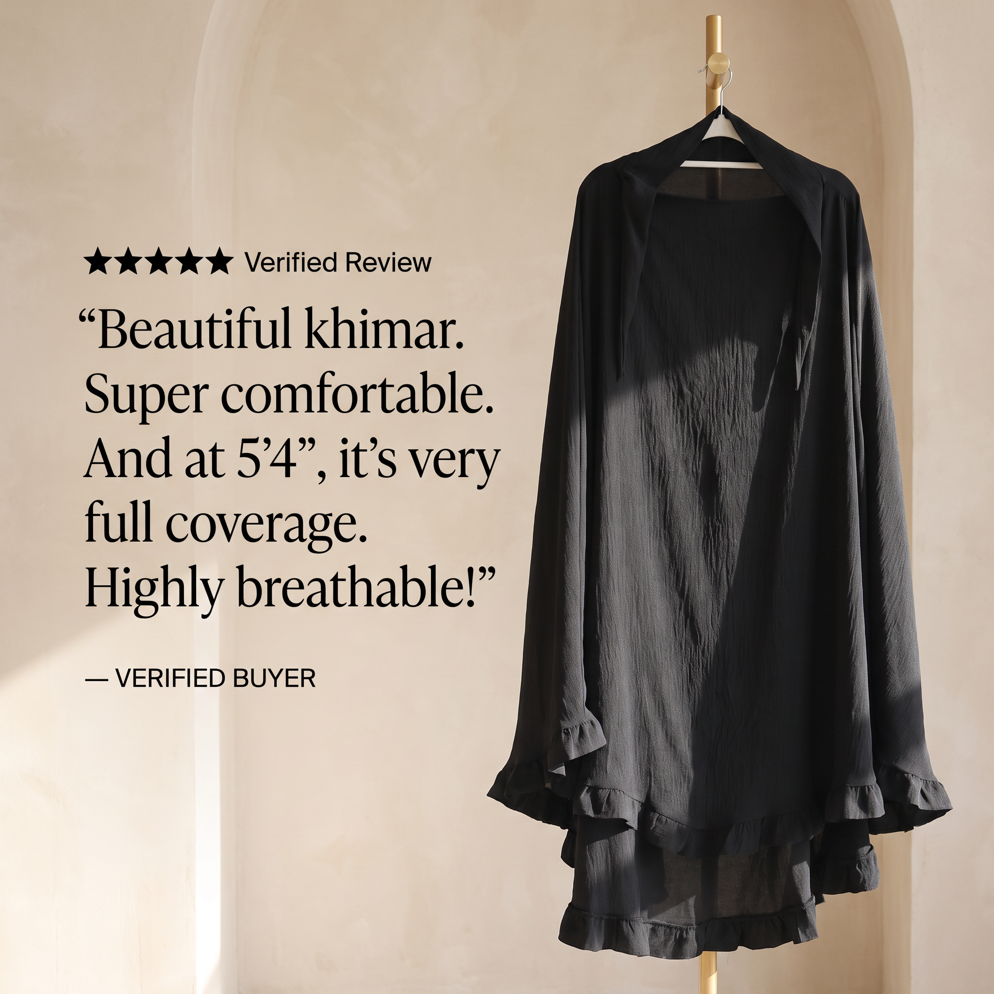 A black sheer khimar-style cover-up dress hanging on a wooden hanger against a warm beige arched wall. Large text on the left reads a verified buyer review praising the garment as beautiful, comfortable, and fully covering.