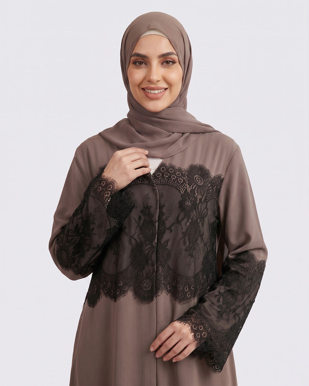 Woman wearing a brown dress with black lace details on a white background