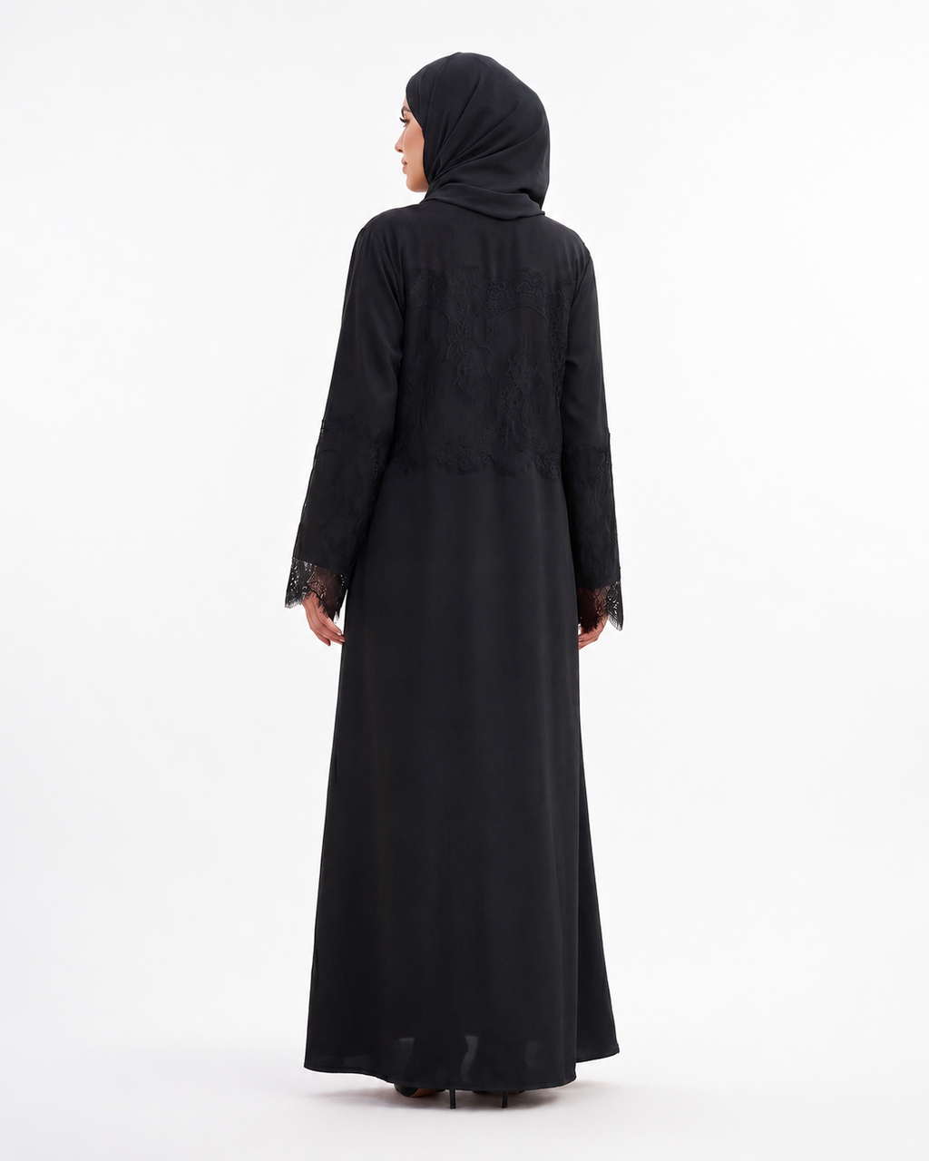 A woman wearing a long black abaya with lace trim on the cuffs and a matching black hijab, shown from the back against a plain white studio background.