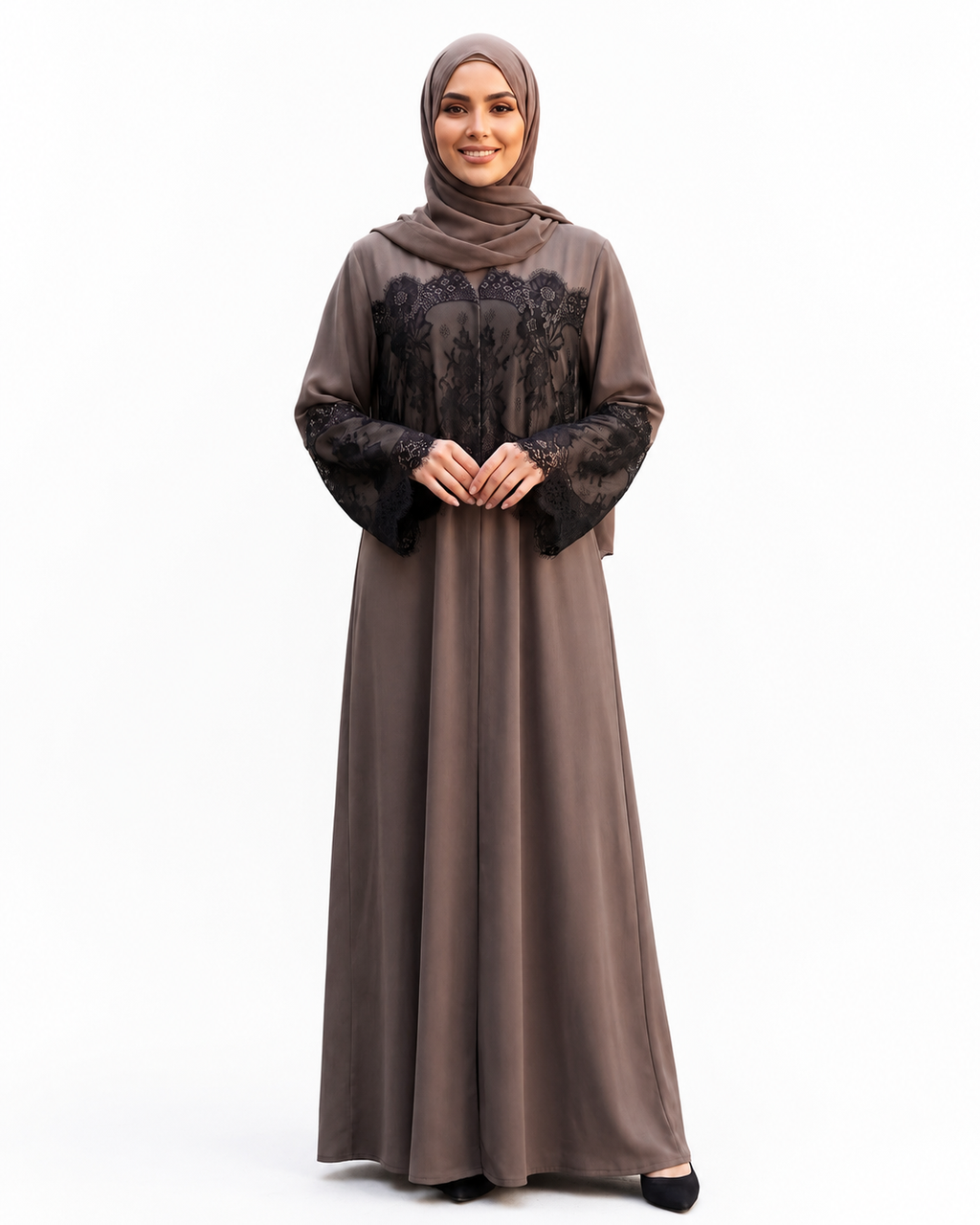 A woman modeling a long taupe-brown abaya dress with black lace sleeves and a matching black lace bodice, paired with a matching taupe hijab, against a plain white studio background.