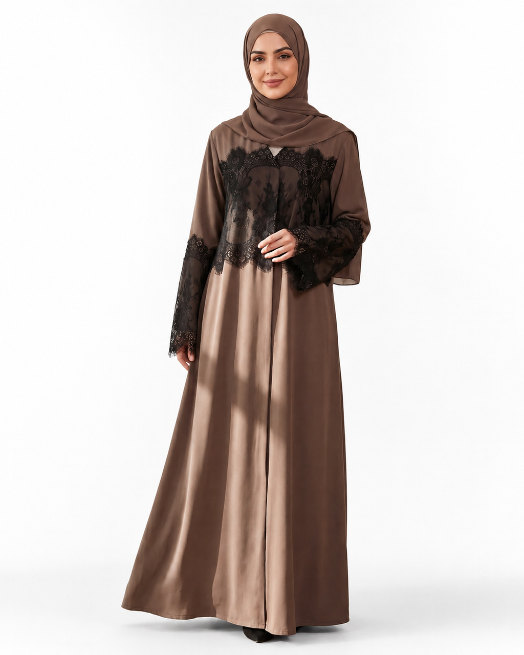 A woman modeling a long-sleeved brown abaya dress with black lace overlay on the bodice and sleeves, paired with a matching brown hijab, against a plain white studio background.