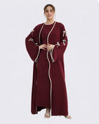 Woman wearing a burgundy dress with white trim on a white background