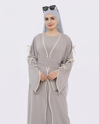 Woman wearing a gray dress with white trim on a white background