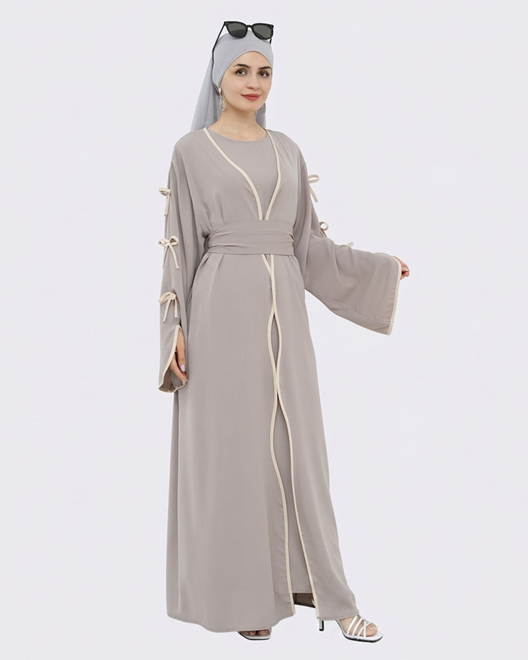 Woman wearing a gray abaya with white accents on a white background